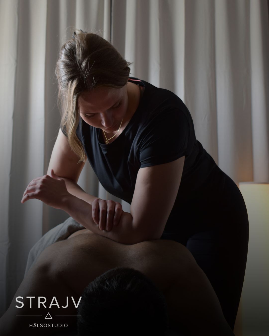 Massageterapeut behandlar arm och skuldra i ett dämpat behandlingsrum